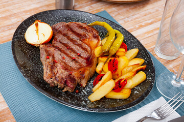 Tasty juicy steak of beef sirloin served with crispy fries, baked green pepper, onion and tomatoes