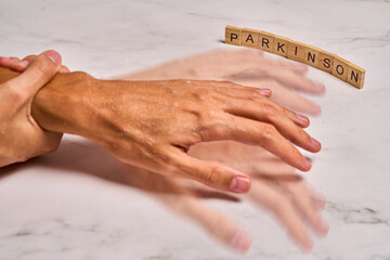 Trembling hand holding glass concept parkinson.