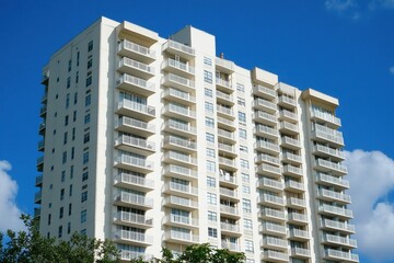 A white high-rise building with balconies against the blue sky, representing real estate Generative AI