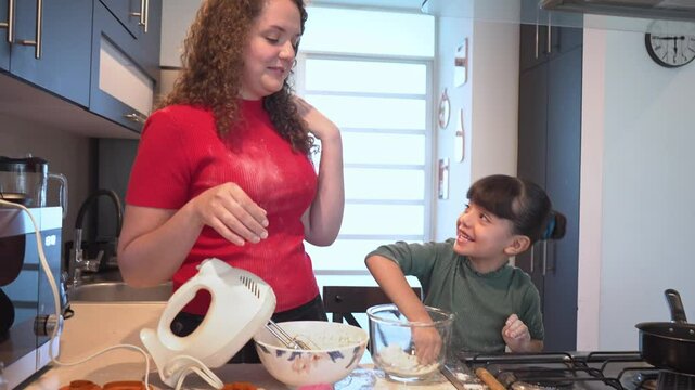 mother and daughter playing with flour while cooking together, mom and kid girl having fun mixing ingredients to bake cookies