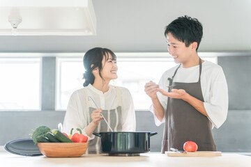 料理を作って味見をする夫婦・カップル・男女（キッチン）

