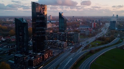 Fototapeta premium Aerial view of modern skyscrapers at sunset with a bustling cityscape and highway below