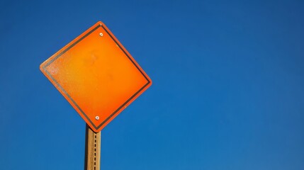 Blank orange diamond road sign against clear blue sky