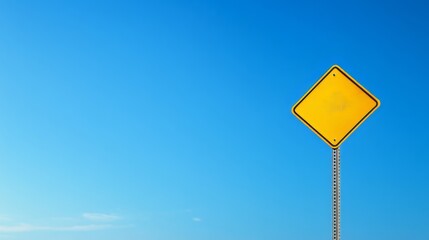Yellow warning sign against clear blue sky on a sunny day