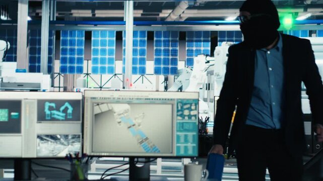 Masked worker in photovoltaics factory commits corporate espionage, stealing proprietary technology using USB stick. Man exploits insider access to copy trade secrets from solar panel plant, camera B