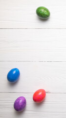 Willow branches and colorful Easter eggs lie on a white wooden table top view