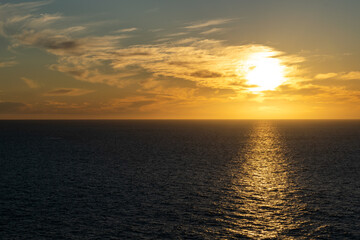 The sun sets on the horizon over the ocean, with colorful and cloudy skies along the coast of Baja California, Mexico.