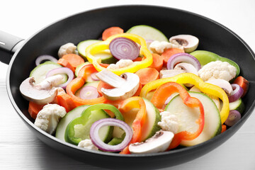 Frying pan with mix of vegetables and mushrooms on white table, closeup