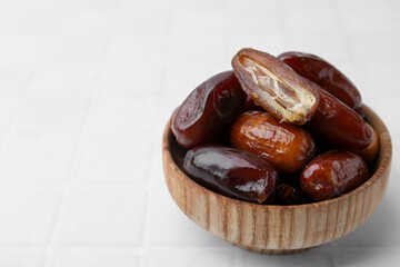 Tasty dried dates in bowl on white table, closeup. Space for text