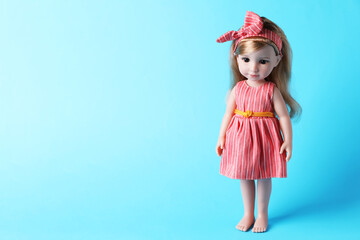 Beautiful doll in dress and headband on light blue background. Space for text