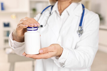 Nutritionist with bottle of weight loss pills in clinic, closeup