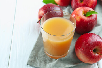 Refreshing apple juice in glass and fruits on white wooden table, closeup. Space for text