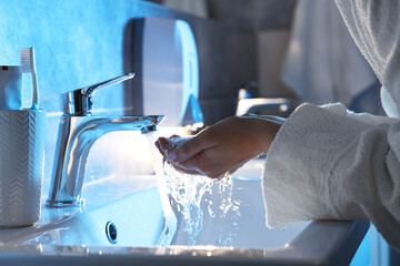 Woman washing her face over sink in bathroom, closeup