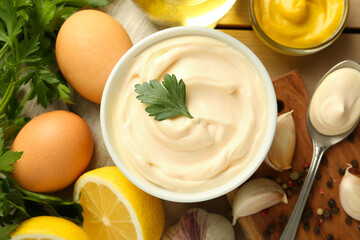 Delicious mayonnaise sauce in bowl and ingredients on wooden table, flat lay