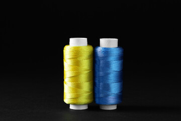 Spools of colorful sewing threads on black background