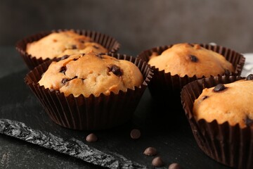 Delicious muffin with chocolate chips on black table, closeup