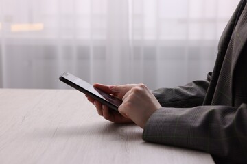 Electronic signature. Woman using smartphone at wooden table indoors, closeup