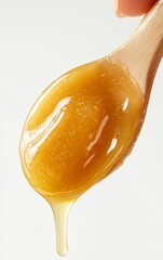 Honey. A close-up shot of honey dripping from a wooden spoon, showcasing its rich texture and golden color