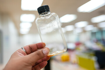 Plastic bottles of iced coffee after pour glass on hand