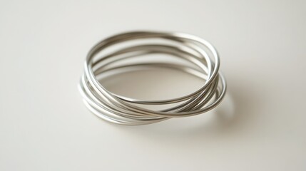 Naklejka premium Close-up of Intertwined Silver Metal Wire Bangles on Clean White Surface