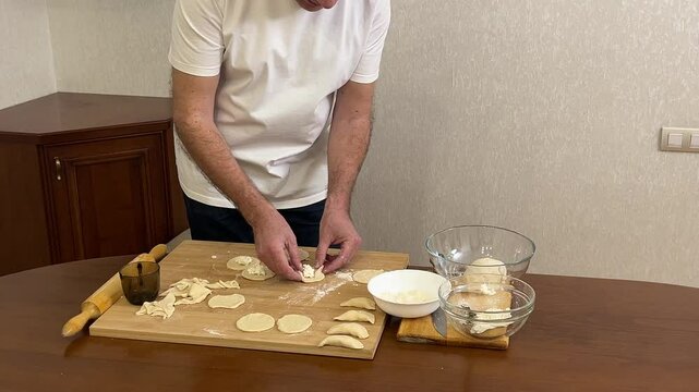 Cooking dumplings, empanadas, vareniki, perogies at home, the man prepares lunch.