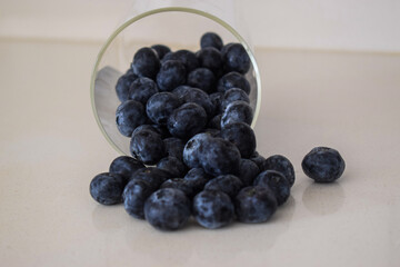 Fresh blueberries spilling from glass jar on kitchen table