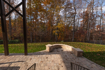 A backyard patio with stone pavers and a curved stone wall, framed by black metal railings. Fallen...