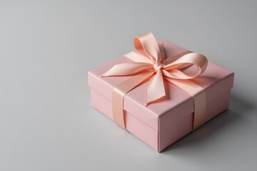 Obraz premium Elegant pink gift box with ribbon on gray background for special occasions