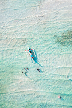 Aerial top down view of bangka boat with people in the turquoise sea, Philippines