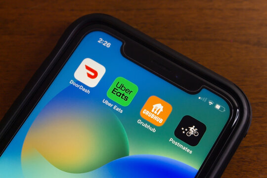 Vancouver, CANADA - Jul 15 2024 : DoorDash, Uber Eats, Grubhub and Postmates icons are displayed on an iPhone. Concept of American major food delivery services.