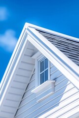 Bright blue sky contrasts with white gabled roof of modern house on a sunny day