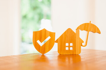 House model with umbrella and shield protect icon on wood table, concepts of contract to buy, get insurance or loan real estate or property background.  © sommart