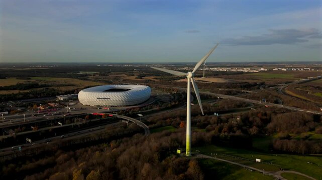 Aerial view of Froettmaninger Mullberg with wind turbine and a clear view of the Allianz Arena in Munich. Bird-eye perspective of the Freimann wind turbine and Munich football arena. 