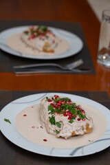 dos platos con Chiles en nogada sobre mesa de madera y fondo desenfocado 