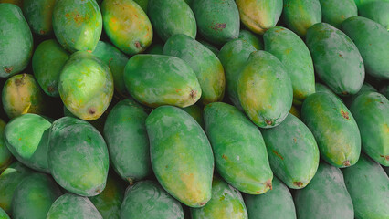 Fresh mangoes in a local market. Green mangoes on the market counter. Exotic Asian fruits.