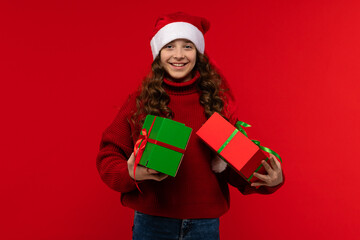 Smiling girl in a Santa hat holds two wrapped gift boxes