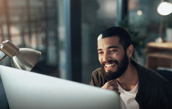 Computer, smile and thinking with designer man in office for website coding or programming deadline. Night, business and planning with happy programmer employee in creative workplace for overtime