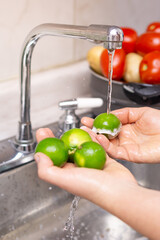 Woman washing organic lemon, food disinfection concept