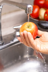 Woman washing organic apple, food disinfection concept
