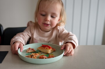 Little girl sitting at the table and eating pizza