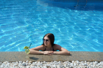 Young woman enjoying a refreshing poolside cocktail on a sunny day