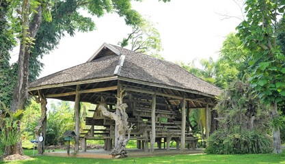 Traditional wooden gazebo in a garden surrounded by trees and nature, with a rural park atmosphere, perfect for summer travel in a peaceful village setting