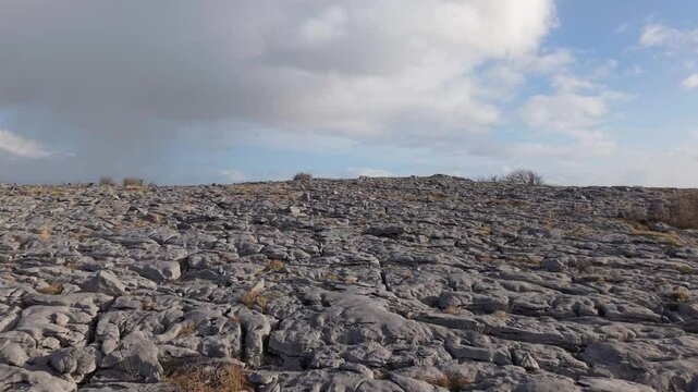The Burren, County Clare, Ireland - The Rugged Limestone Terrain Features Characteristic Cracks, Sparse Vegetation, and a Partly Cloudy Sky Overhead - Drone Flying Forward