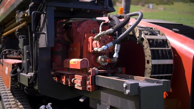 horizontal directional drilling machine hydraulic motor visible, showing hoses, mechanical parts in operation The red steel emphasizes the power behind underground boring and pipe installation