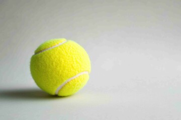 A single bright yellow tennis ball is resting on the surface