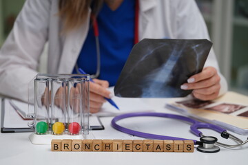 A healthcare professional is carefully examining an Xray to determine a diagnosis for bronchiectasis