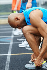 Man, fitness and tying with shoes on stadium track for running competition, sprint or race. Male...