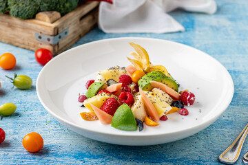 Mixed fruit salad with fruits such as banana, strawberry and pineapple on a white porcelain plate