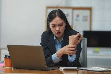 Asian businesswoman suffering wrist pain at office desk