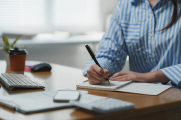 Fototapeta premium Office worker writing notes in notebook at desk